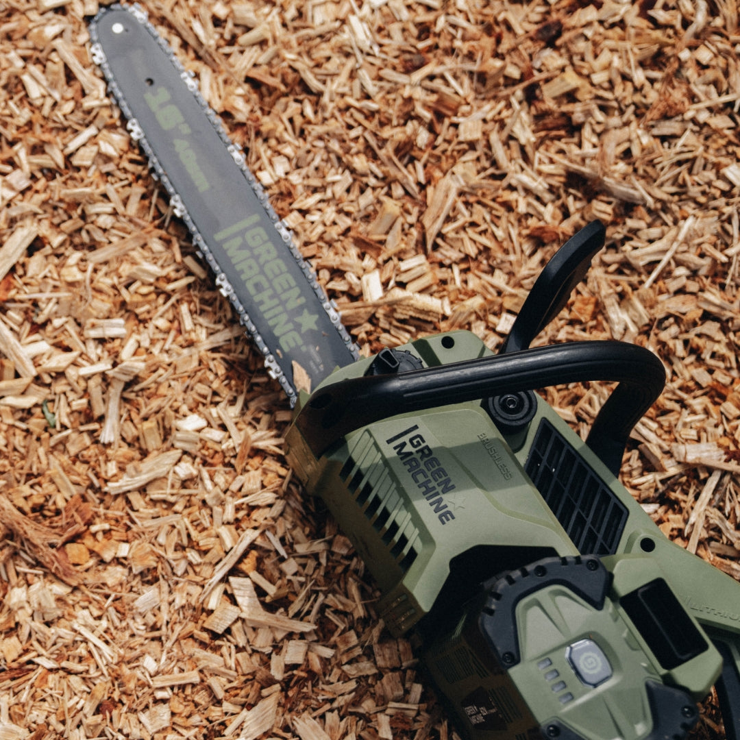 Green Machine 16 inch chainsaw laying on ground.